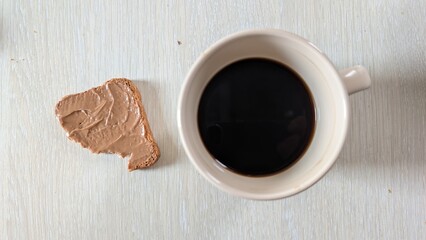 A delicious Coffee and a delightful Biscuit elegantly placed on a Wooden Table surface