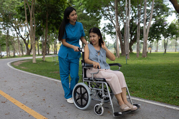 A smiling nurse assists a senior woman in a wheelchair outdoors, showing compassion, support, and togetherness in a caring healthcare environment.
