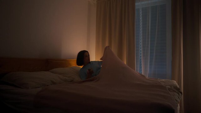 Woman laying down in bed to rest after long day. Person going to sleep.