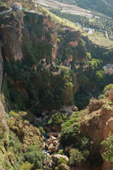 view of ancient ruins in the rocky mountains, full of vegetation, trees and rocks, with a small stream, at sunset