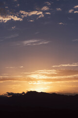 beautiful sunset over the silhouette of the mountains with a slightly cloudy sky