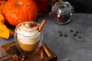 A glass of autumn pumpkin latte with whipped cream and spices. Coffee with pumpkin and cinnamon on a dark background, copy space