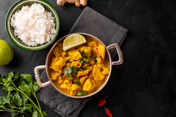 Chicken in curry sauce and rice on black background, Indian food top view