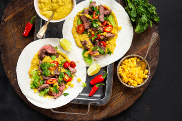 Mexican tacos, tortilla with beef, vegetable sauce, corn and tomatoes on the table top view