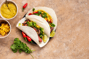 Mexican tacos, tortilla with beef, vegetable sauce, corn and tomatoes on the light background top view copy space for text