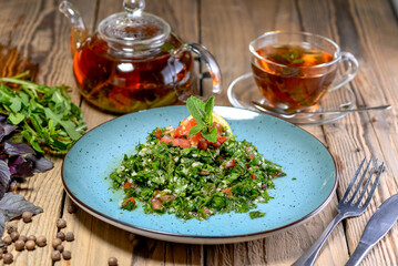 oriental salad with greens, nuts, tomatoes and tea on the background