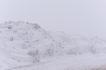Massive snow piles along roadside in winter landscape during heavy foggy weather. concept of harsh winter weather