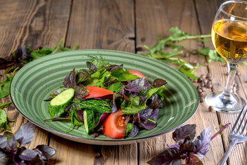 salad with greens, tomatoes, cucumber and basil in a green plate