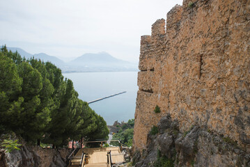Awesome view of the Kizil Kule (Red Tower) from fortress walls of Alanya Castle in Turkey. The Mediterranean Sea is visible in background. The octagonal red brick tower is a popular tourist attraction