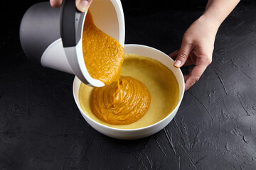 Pumpkin pie filling being poured into a crust, showcasing the rich texture and vibrant color, with a dark background enhancing the culinary scene and inviting atmosphere