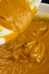 Creamy pumpkin pie filling being mixed in a bowl with a spatula, showcasing a rich texture and vibrant orange color, perfect for holiday baking and seasonal desserts