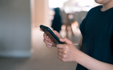 Close up,Young boy hands using mobile smart phone with blurry living room background,Teen boy using smartphone during summer break at home talking, texting messages, ,playing games online social media