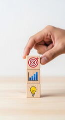 Hand stacking wooden cubes with strategy and innovation icons. Minimalist business growth and planning concept. Clean and organized visual layout of success metrics.