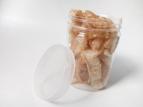 Kerupuk kulit sapi or rambak or beef skin crackers in plastic jar isolated on white background. Crackers with a savory and crispy taste