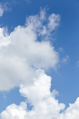 Fluffy white clouds scattered across a bright blue sky, creating a serene atmosphere, perfect for backgrounds or nature-themed designs with copy space