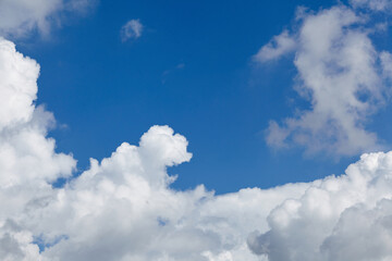 Bright blue sky filled with fluffy white clouds, creating a serene atmosphere, perfect for backgrounds, with ample copy space for text or design elements