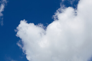 Fluffy white clouds against a vibrant blue sky create a serene atmosphere, showcasing the beauty of nature and the tranquility of a clear day with open space