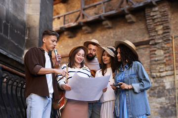 Guide with microphone and group of tourists on city street during excursion, low angle view