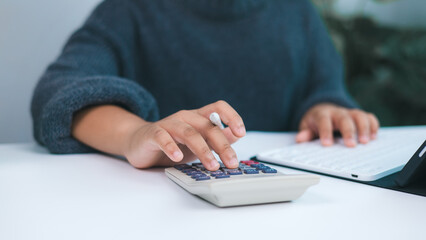 Person working on financial tasks with calculator and digital tablet, symbolizing accounting, budget management, tax preparation, and personal or small business financial services.