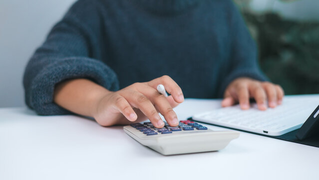 Person working on financial tasks with calculator and digital tablet, symbolizing accounting, budget management, tax preparation, and personal or small business financial services.