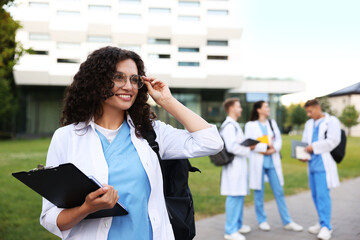 Fototapeta premium Medical student in uniform with clipboard outdoors, selective focus