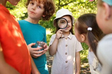 Obraz premium Children with magnifying glass and jar in nature