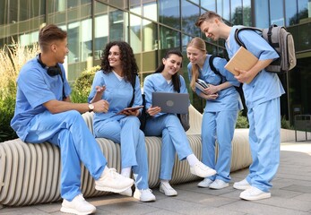 Fototapeta premium Group of medical students in uniforms studying together near building outdoors