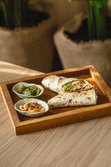 Grilled tortilla wrap with jalapeno and spicy dips on wooden tray
