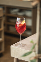 Red cocktail with orange slice and ice in elegant wine glass