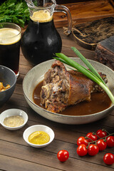 Portion of baked pork knuckle with sauce and spring onion