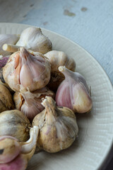 fresh garlic bulbs on a ceramic plate, rustic kitchen scene. themes: organic food, natural medicine, cooking ingredients, rustic lifestyle, homegrown produce.