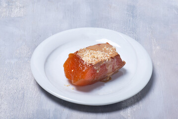 High angle studio photo of pumpkin dessert, a traditonal Turkish dessert called tahinli kabak tatlısı on white wooden table