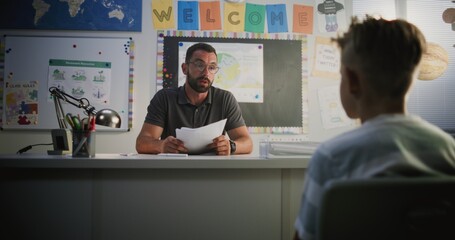 Obraz premium Male Teacher Presenting School Exam Results to Primary School Boy, Discussing Poor Performance, Low Grades and Behavior with Student. Extracurricular Meeting to Support Child's Learning. Dolly Shot.