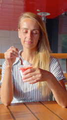 Blonde Woman Enjoying Strawberry Sundae at Outdoor Cafe in Summer Light
