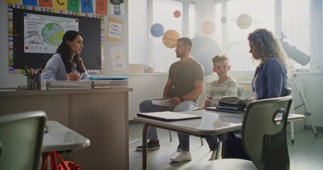 Female Teacher Giving School Exam Results of Young Boy to His Parents. Teacher and Parents Discussing Academic Failure of Primary School Student in Classroom. Meeting to Support Child's Development.