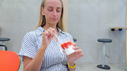 Smiling Woman Eating Strawberry Sundae at Modern Cafe Table