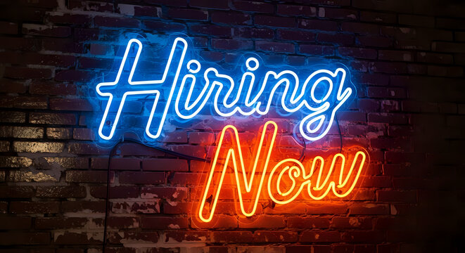 A neon sign on a brick wall that reads hiring now with blue and orange lights in a dark background