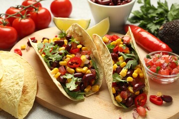 Tasty vegetarian tacos and ingredients on table, closeup