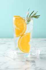 Refreshing soda water with orange slices and rosemary on white marble table, closeup