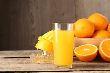 Tasty orange juice, fresh fruits and juicer on wooden table, space for text