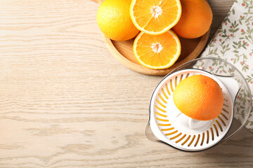 Making juice. Juicer and fresh oranges on wooden table, flat lay. Space for text