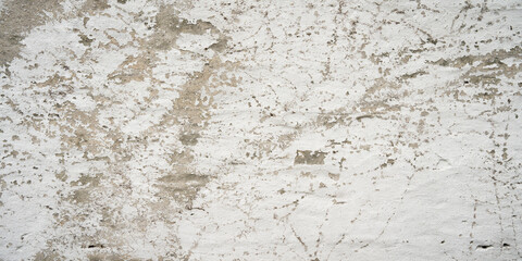 Aged gray concrete wall with peeling white color. Abstract background with cracked white plaster texture.