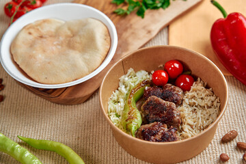 Delicious Mediterranean Platter Featuring Grilled Meatballs, Rice, Fresh Vegetables and Warm Pita Bread Served in a Cozy Setting