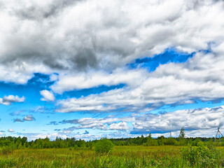 Expansive sky over a green field with fluffy clouds and vibrant blue hues at midday