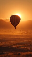 Naklejka premium Sunrise hot air balloon over a hazy landscape