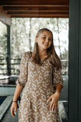 A girl in a flower dress stands near the wall
