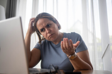 Obraz premium Confused businesswoman looking at laptop screen while working from home office, facing work challenge.