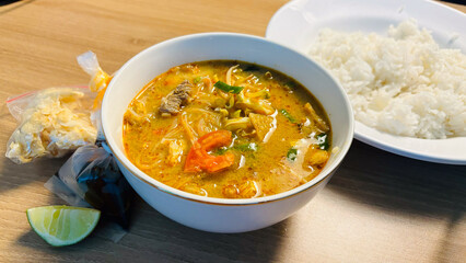 Traditional Indonesian Soto Daging a beef soup with rice lime and crackers on a wooden table.