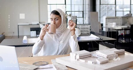 Woman architect reaching for ceramic mug after laptop prompt, sipping while reviewing scale model - Powered by Adobe