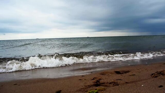 "The waves of the sea talk to the shore". The video shows a picturesque seascape. The waves gently roll onto the shore and crash noisily against the sandy or rocky coast.